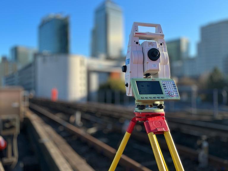 Total station set up over DLR track with Canary Wharf behind